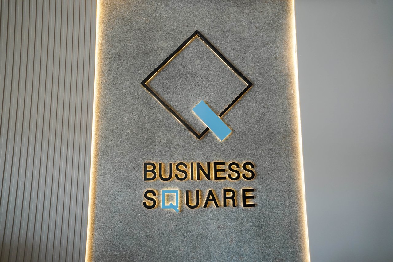 The Business Square diamond mark set into a backlit stone wall