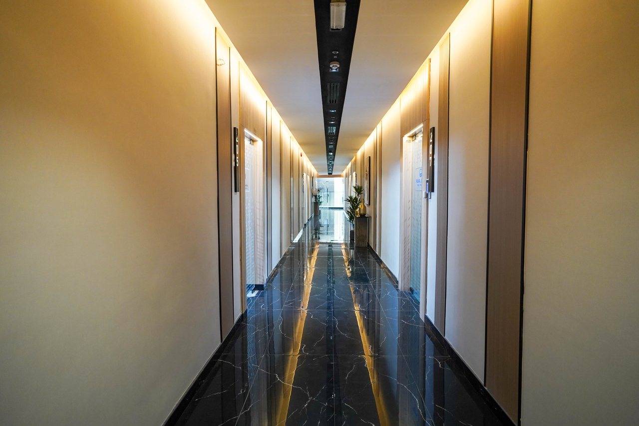 Long office corridor perspective with a continuous lit ceiling groove