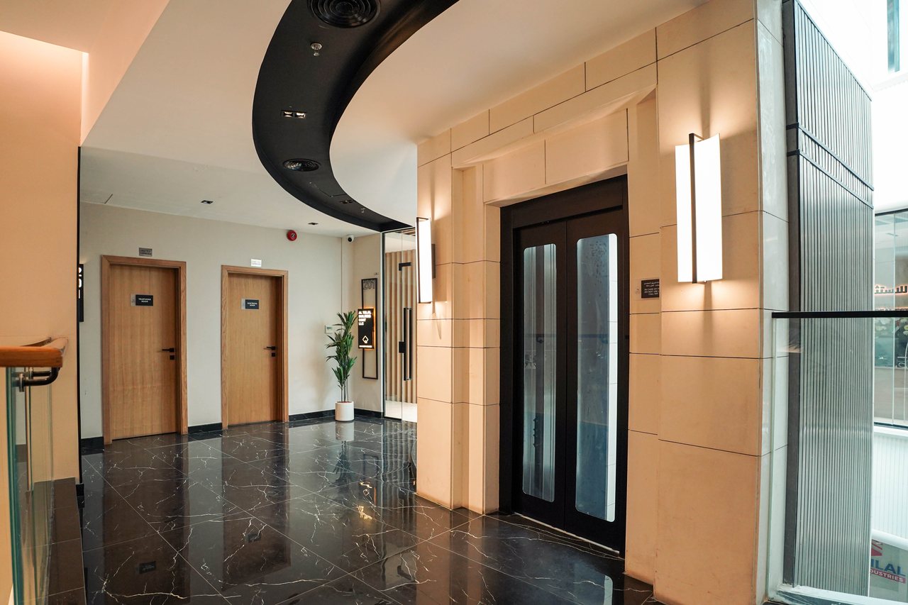Office entrance doors along a corridor with backlit stone and timber panelling