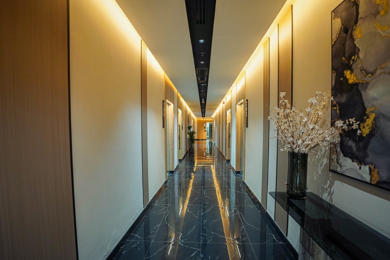 Office corridor with black marble flooring, warm wall lighting and framed artwork