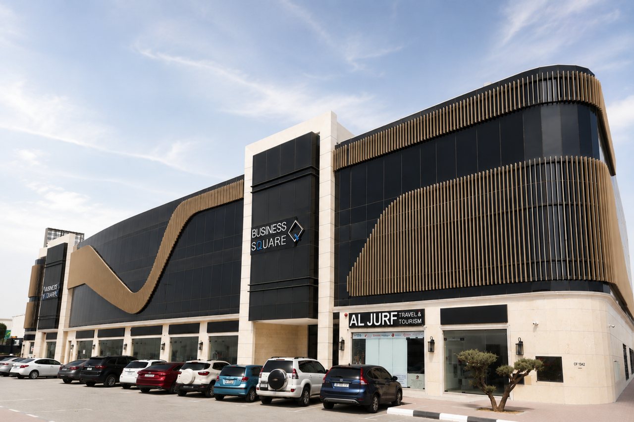 Corner approach to Business Square with the sweeping bronze band running across the dark glass façade