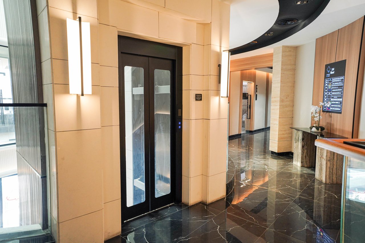 Lift entrance framed by backlit stone panels on a Business Square floor lobby