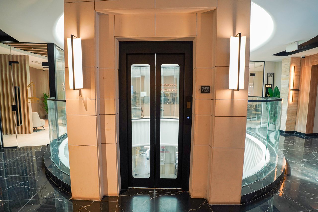 Stone-clad lift portal with linear lighting on a Business Square office floor