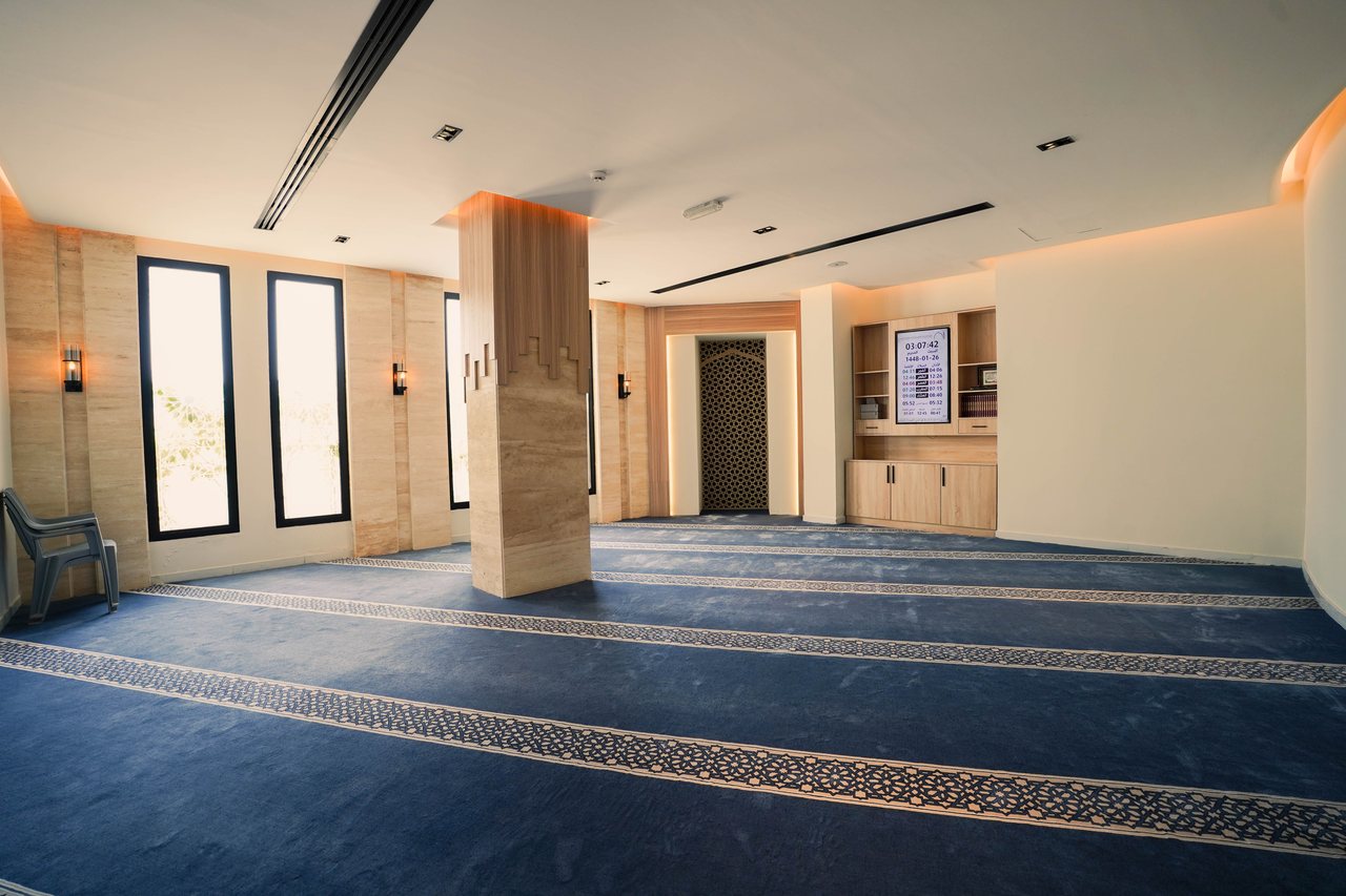 Prayer hall interior with patterned carpet and mashrabiya screen detail