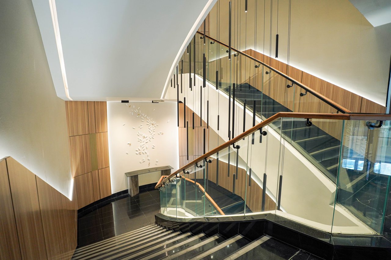 Stair landing framed by the sculptural relief wall and timber cladding