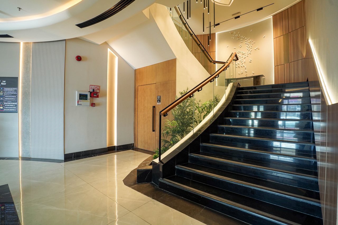 Feature staircase rising beside the planted lobby edge